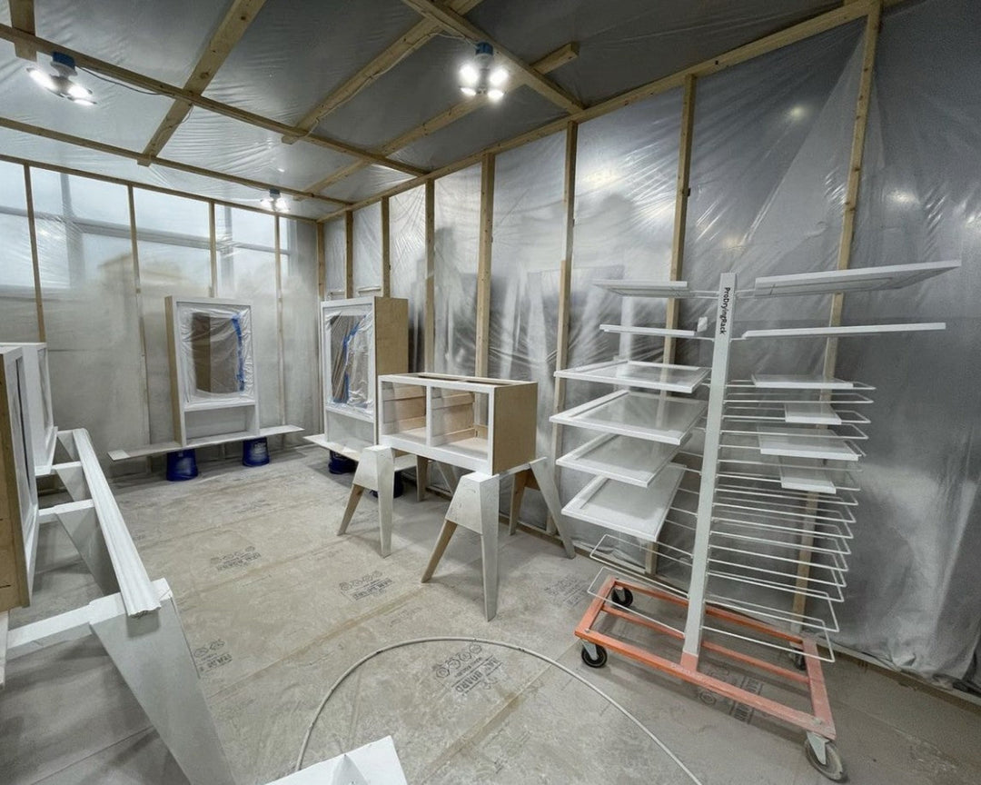 Room with wooden shelves and a cart, covered with plastic sheeting.
