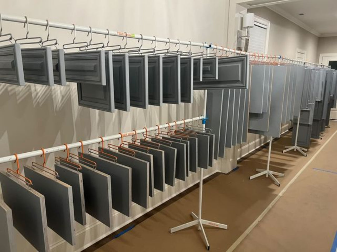 Multiple levels of metal drying rack lines holding cabinet doors