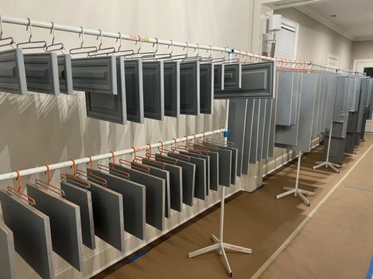 Multiple levels of metal drying rack lines holding cabinet doors