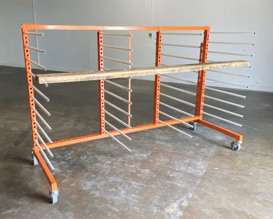 Orange metal rack with 4 towers and 10 levels of white shelves, holding a piece of long plywood