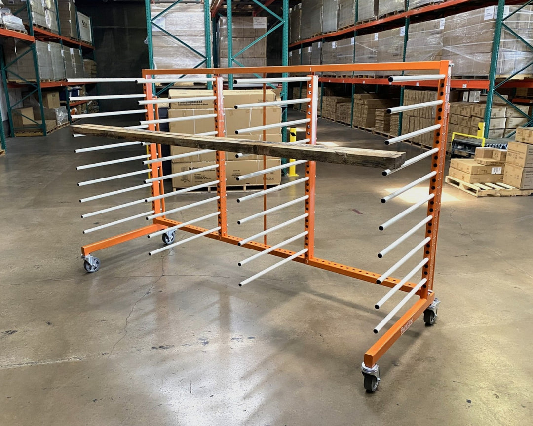Orange metal rack with 4 towers and 10 levels of white shelves, holding a piece of long plywood in a warehouse setting