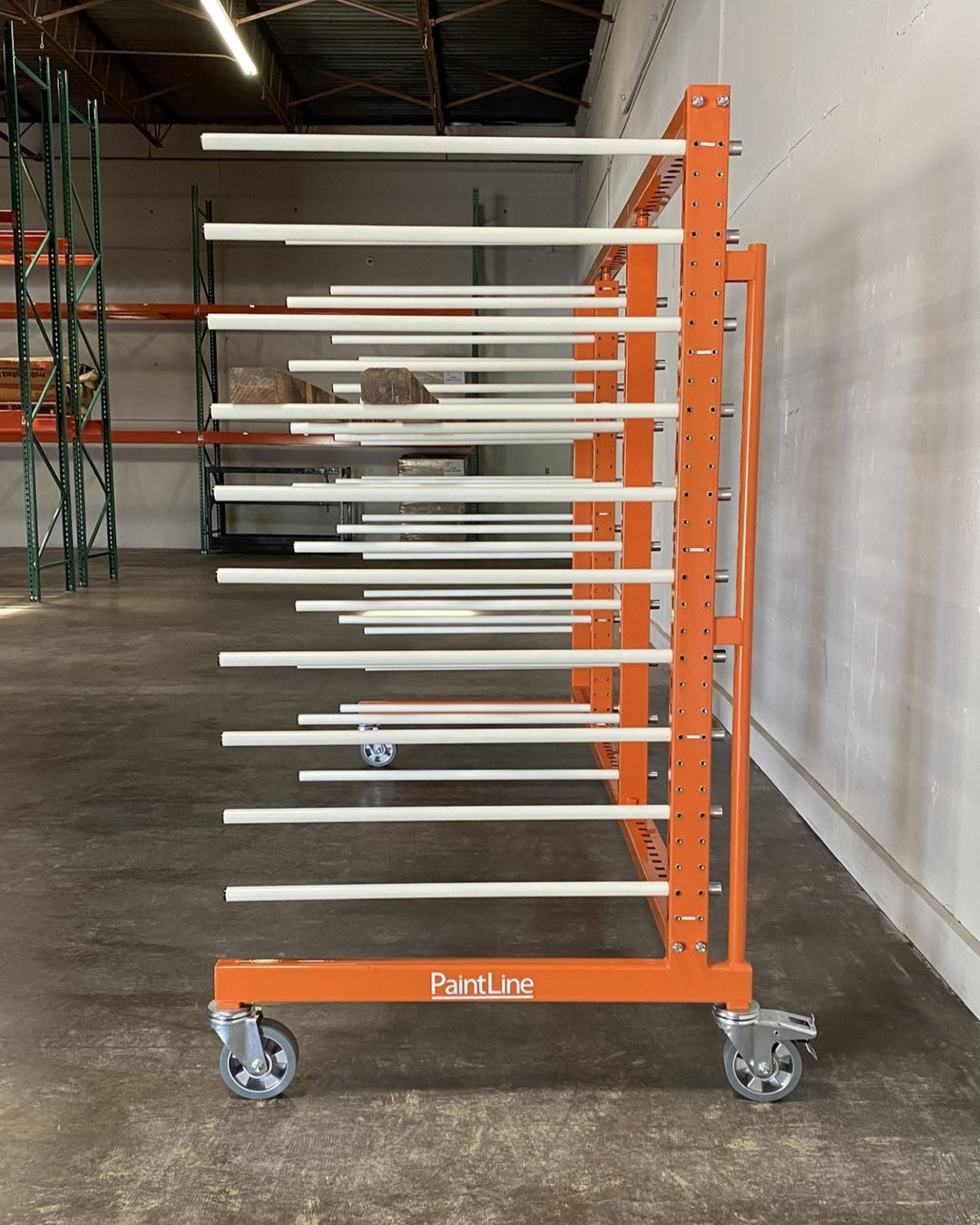 Side view of an orange metal rack with 4 towers and 10 levels of white shelves, holding a piece of long plywood
