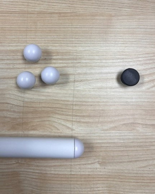 A close up image of a white shelf tube, with three white shelf caps and one black shelf cap, sitting on a wooden table.