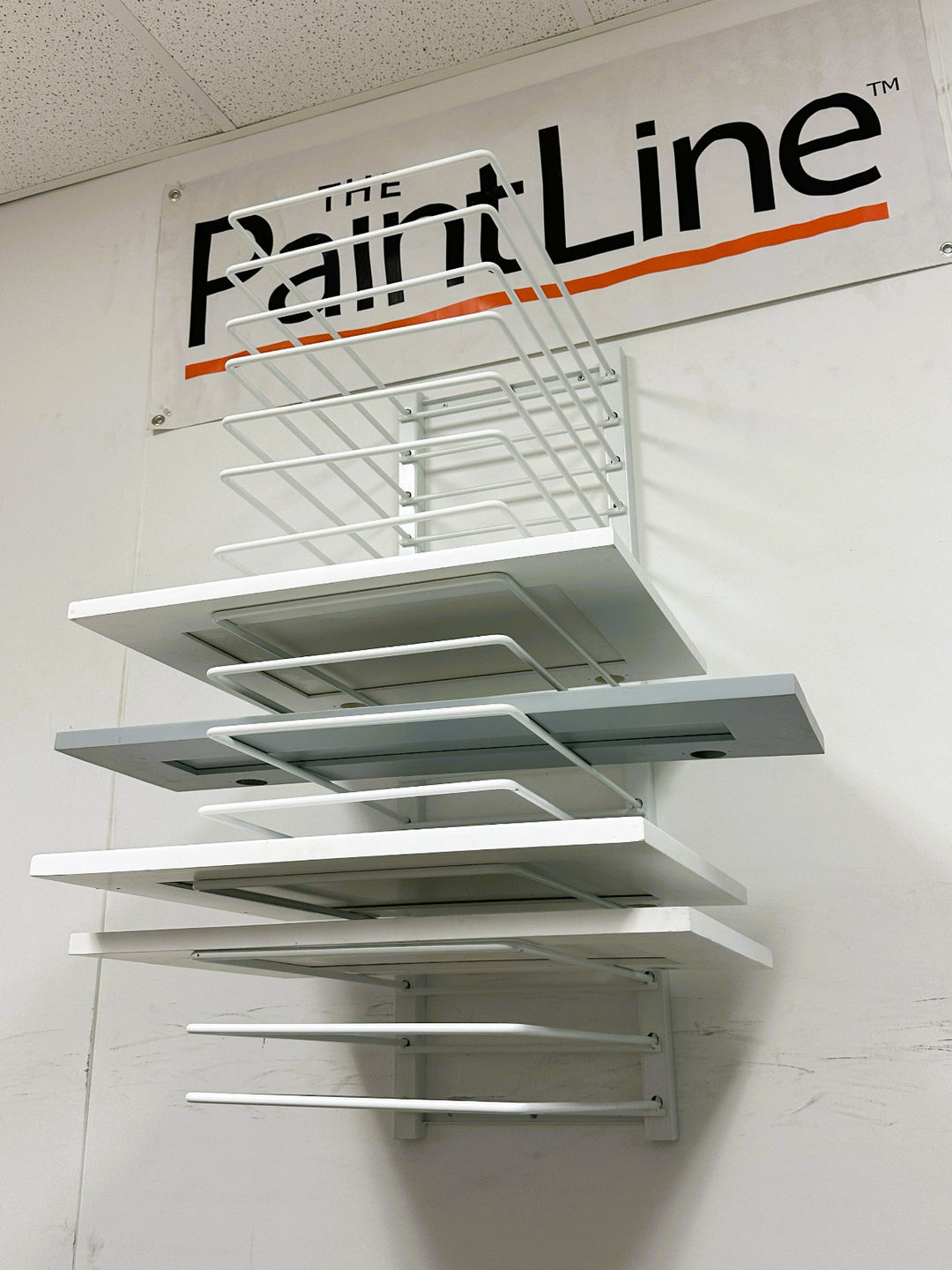 15-shelf wall mounted cabinet door drying rack, holding a few cabinet doors, with a PaintLine logo banner above it.