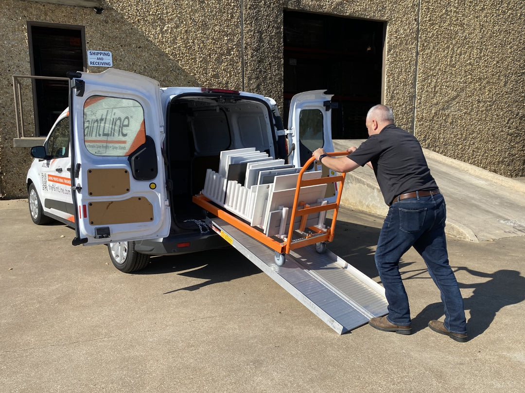 Man loading a cart with finished cabinet doors into a van