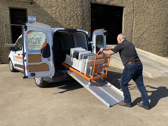 Man loading a cart with finished cabinet doors into a van
