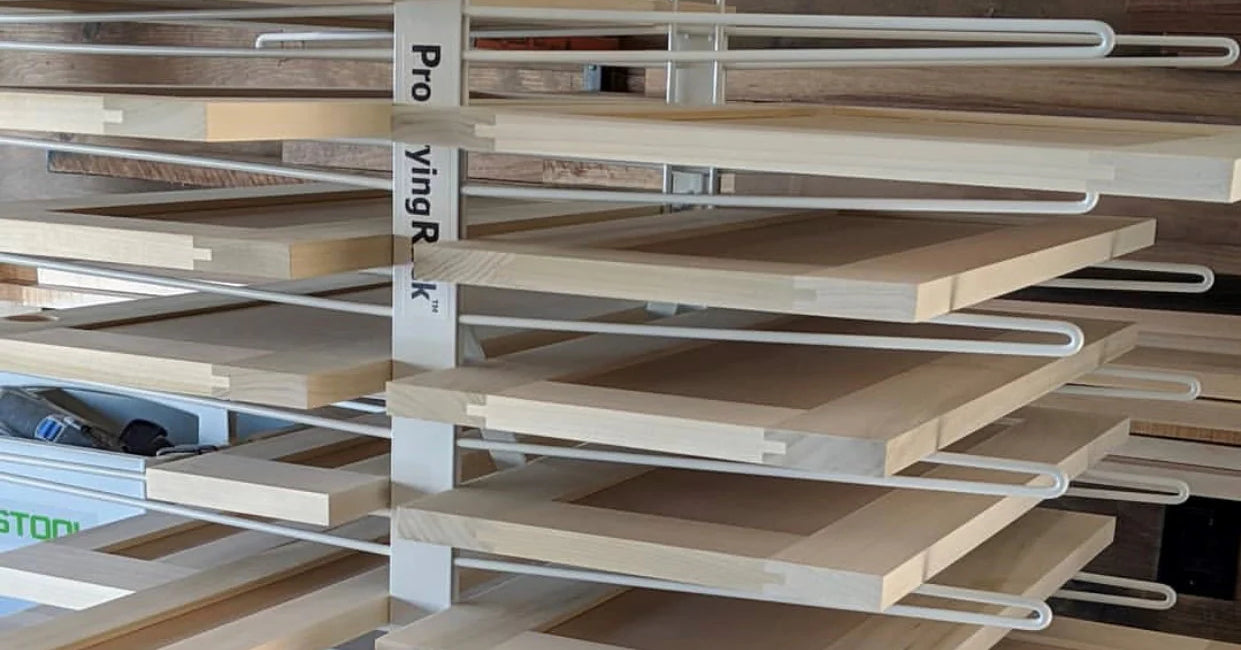 Closeup of a white metal drying rack holding unfinished wood cabinet doors