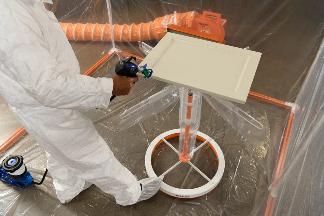 SPRAYTWIRLYHD (SPTYHD) BEING ROTATED WITH FOOT TO SHOW HANDS-FREE OPERATION AND USED TO SPRAY WHITE CABINET DOOR INSIDE SPRAY BOOTH