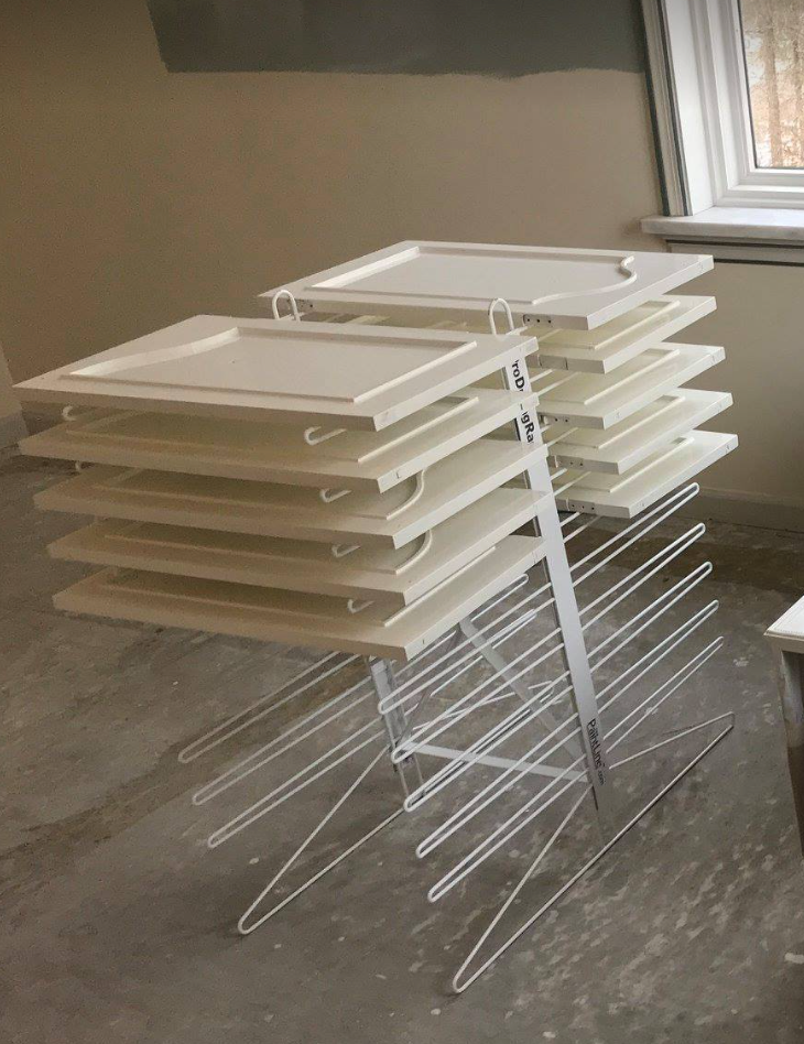 PRODRYINGRACK TT (PDRTT) IN USE ON FLOOR WITH WHITE CABINET DOORS DRYING ON RACK