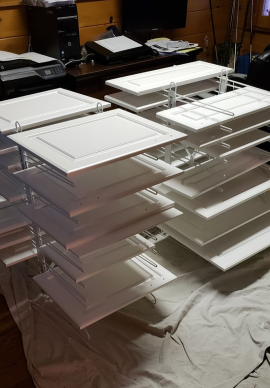 2 PRODRYINGRACK TT (PDRTT) IN USE ON FLOOR WITH WHITE CABINET DOORS DRYING ON RACK