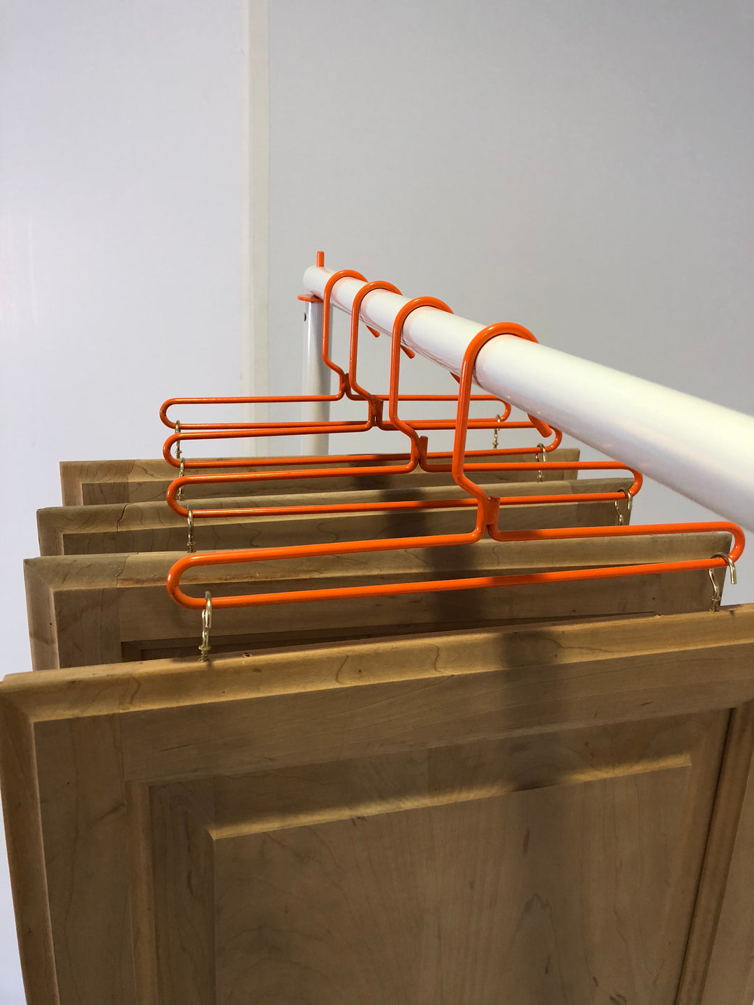 PRODRYINGRACK SD (PSDR) SERIES STANDARD HANGERS IN USE WITH CUP HOOKS AND BROWN CABINET DOORS HANGING TO DRY